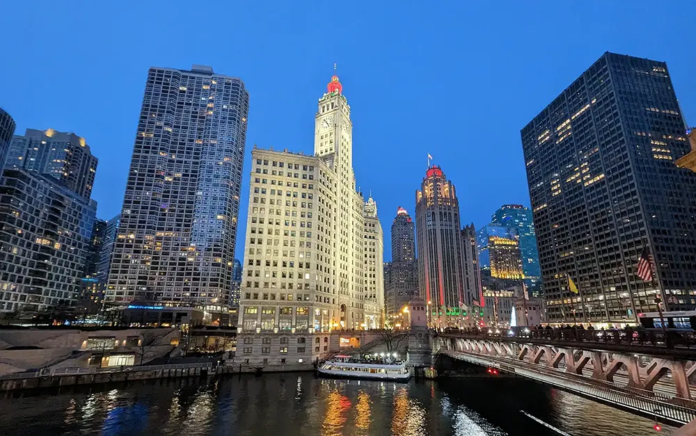 The Chicago Magnificent Mile lit up at night with a boat and bridge.