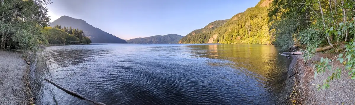 Lake Crescent From Marymere Falls Trail Panorama A beautiful sunset panorama of Lake Crescent from the Marymere Falls trail. Sunlight cascades over the mountains while ripples move across the clear blue lake.