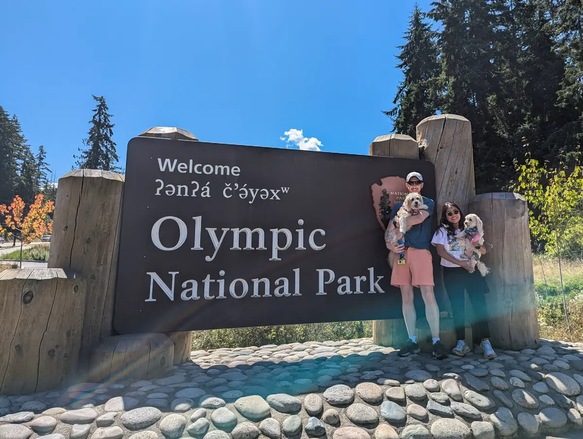 Olympic National Park Sign Port Angeles Visitors posing with their dogs at the Olympic National Park entrance sign, marking the start of their Peabody Creek Trail adventure.