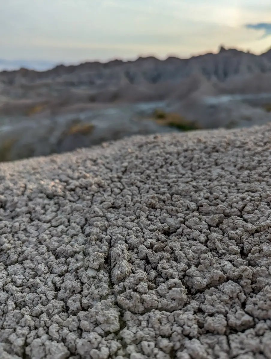 Landscape Of Badlands Close-up texture of cracked, dry, light-colored soil and sediment typical of the Badlands landscape.