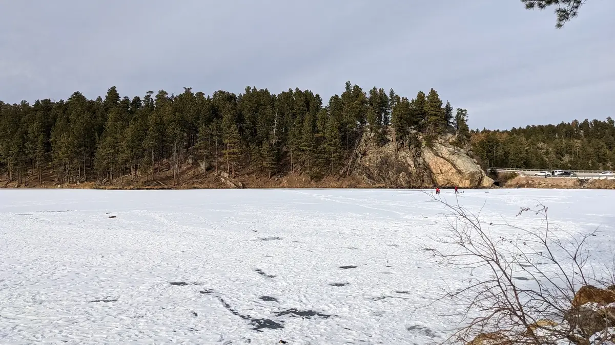Ice fishers on the frozen surface of Horse Thief Lake in South Dakota during a scenic winter day near Mount Rushmore.