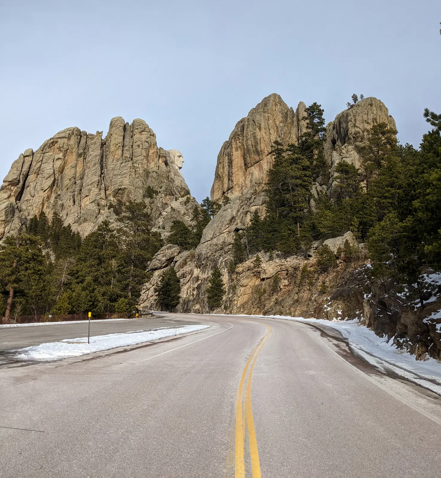 Side profile view of George Washington’s face on Mount Rushmore as seen from a winding road in the Black Hills during winter.