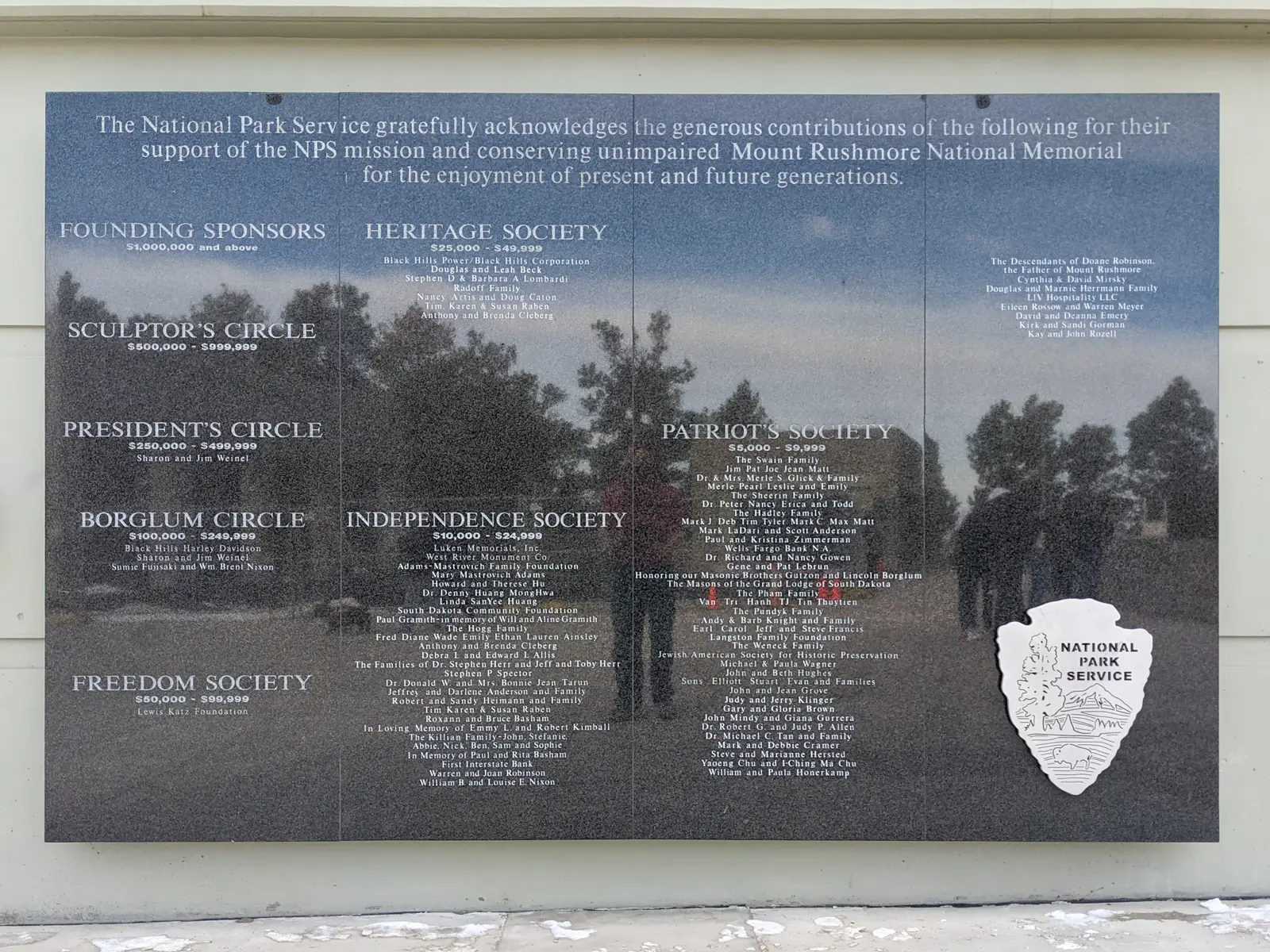 Close-up of the donor recognition plaque at Mount Rushmore featuring the National Park Service arrowhead logo.