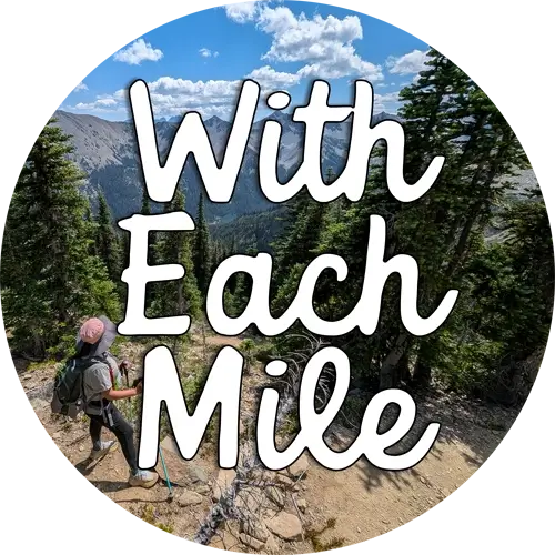 A circular logo for the travel blog "With Each Mile," featuring a photo of a hiker from behind in a mountainous landscape. Overlaid text reads "With Each Mile" in white script.