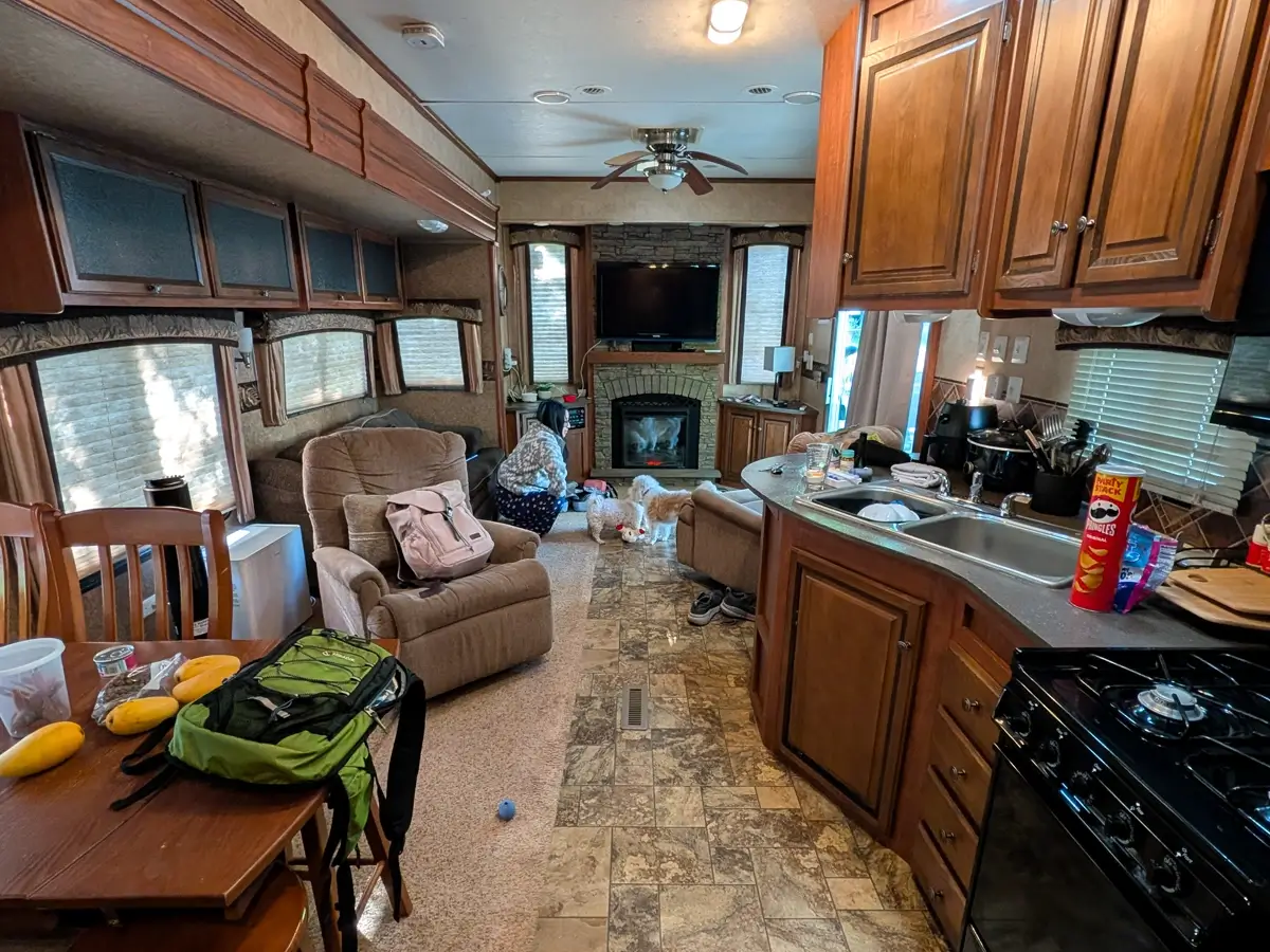 The spacious interior of a travel trailer showing a kitchen and living area, where Minerva and their two dogs, Toby and Lily, are relaxing after a day of hiking.